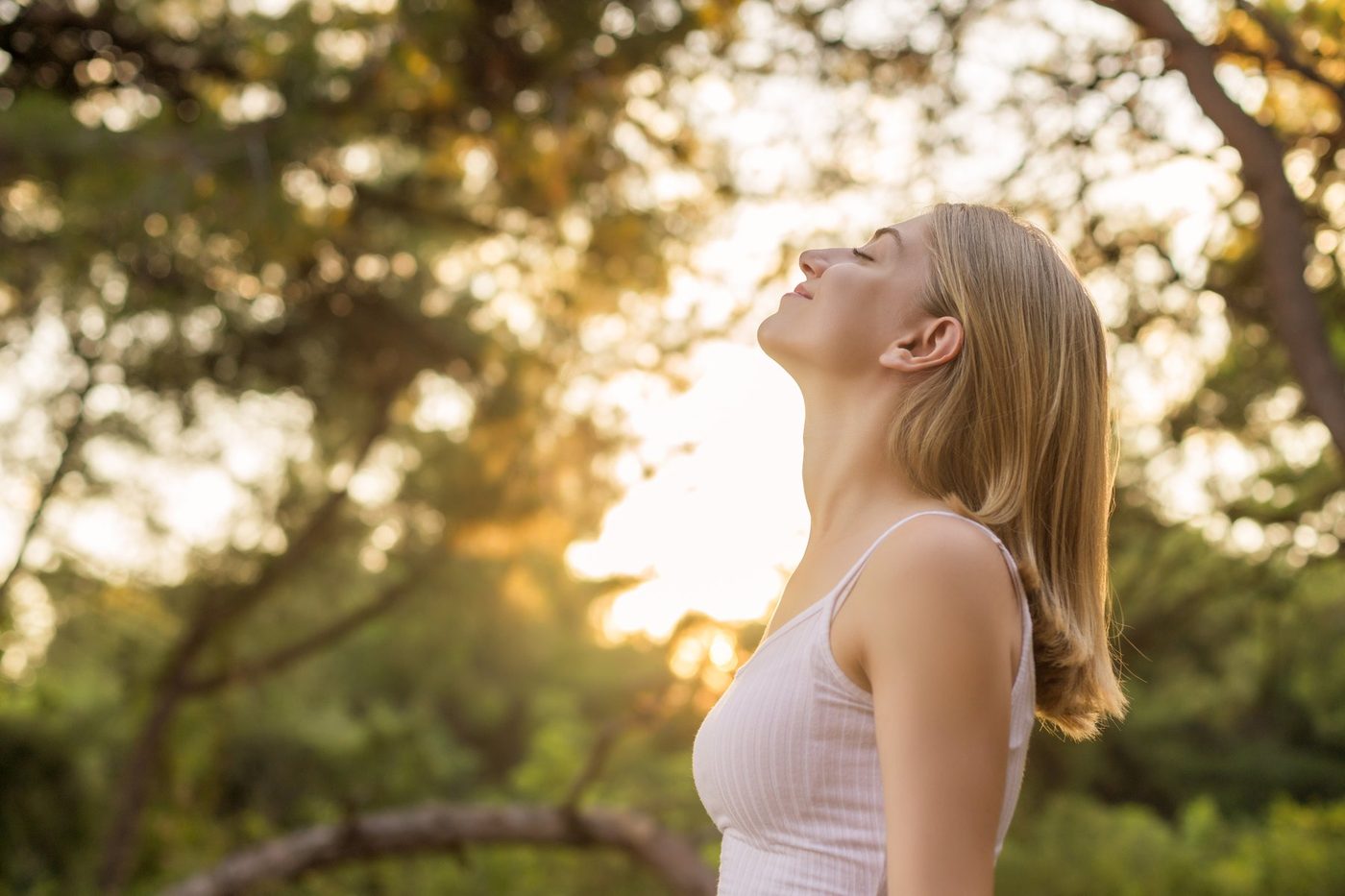 A woman breathing outdoor air at sunset